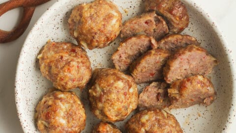 Overhead shot of a bowl of sausage meatballs, with two of them sliced.