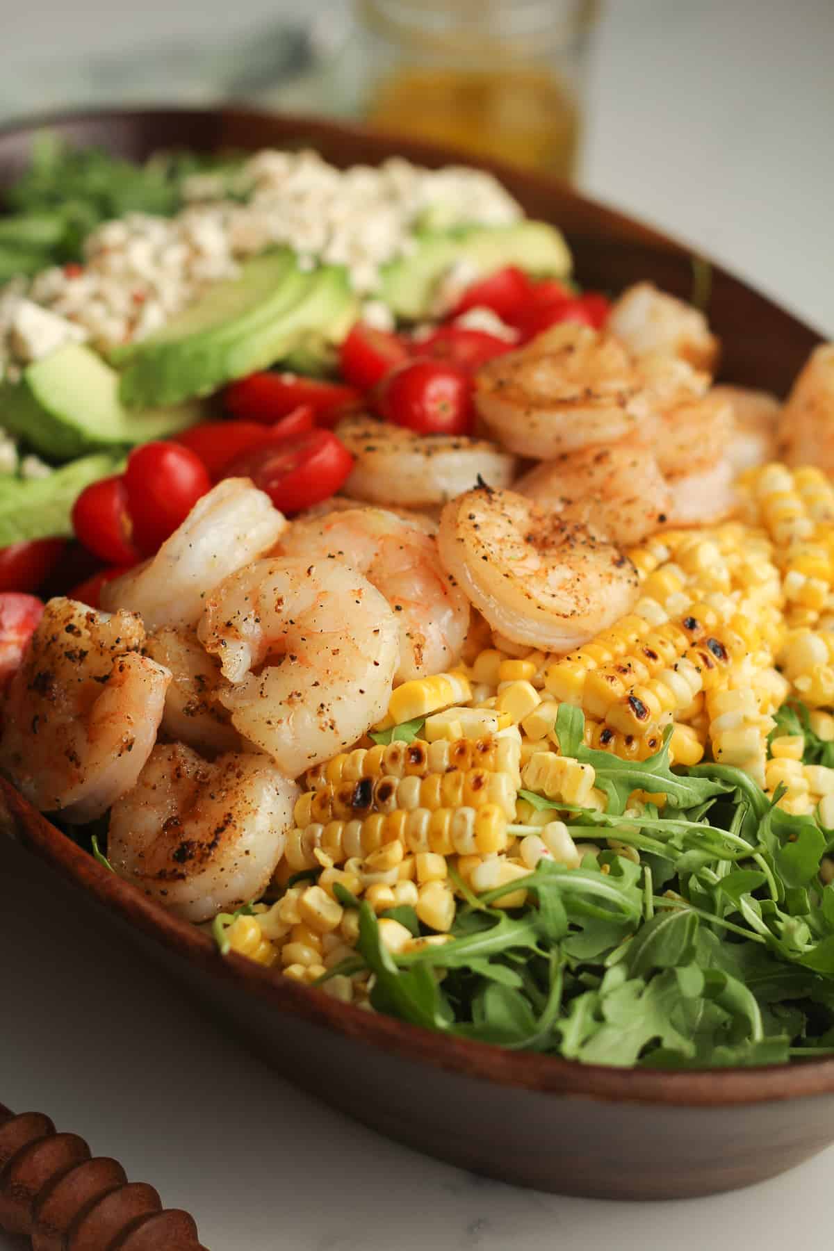 Side shot of a wooden bowl of shrimp salad.