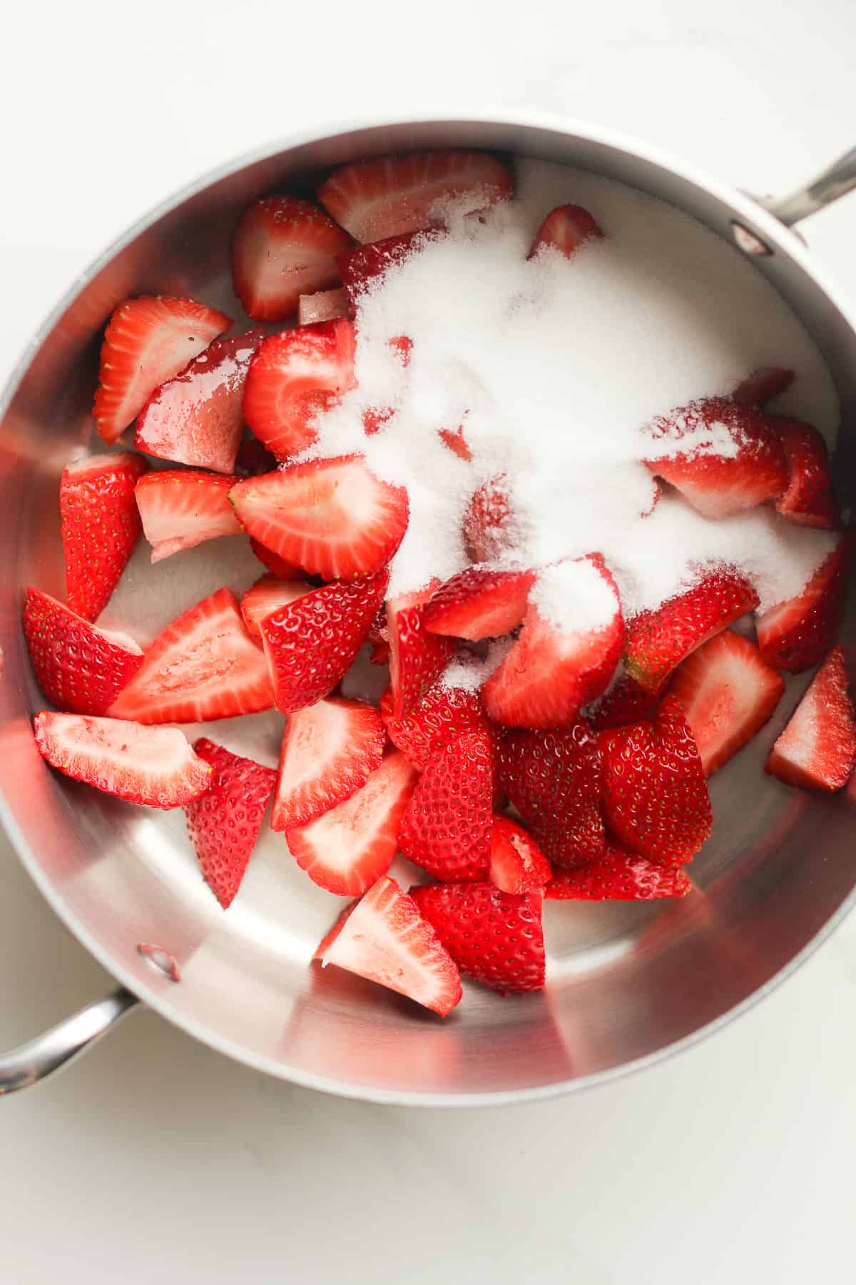 A pan of quartered strawberries with sugar.