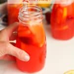 A hand on a jar of strawberry vodka lemonade.