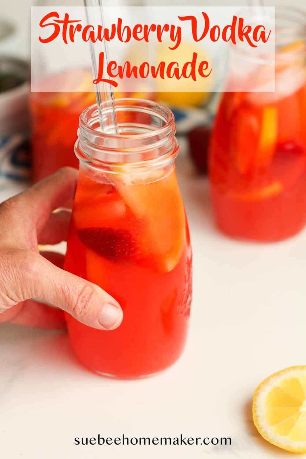 A hand on a jar of strawberry vodka lemonade.