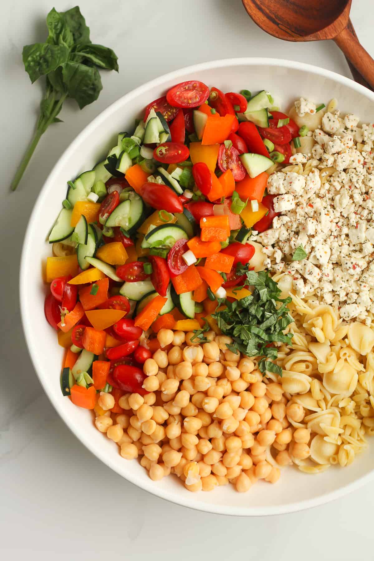 A bowl of the pasta salad ingredients, separated by ingredient.