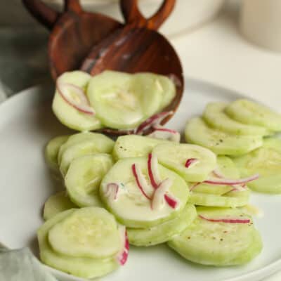 Two wooden spoons serving sliced cucumbers.