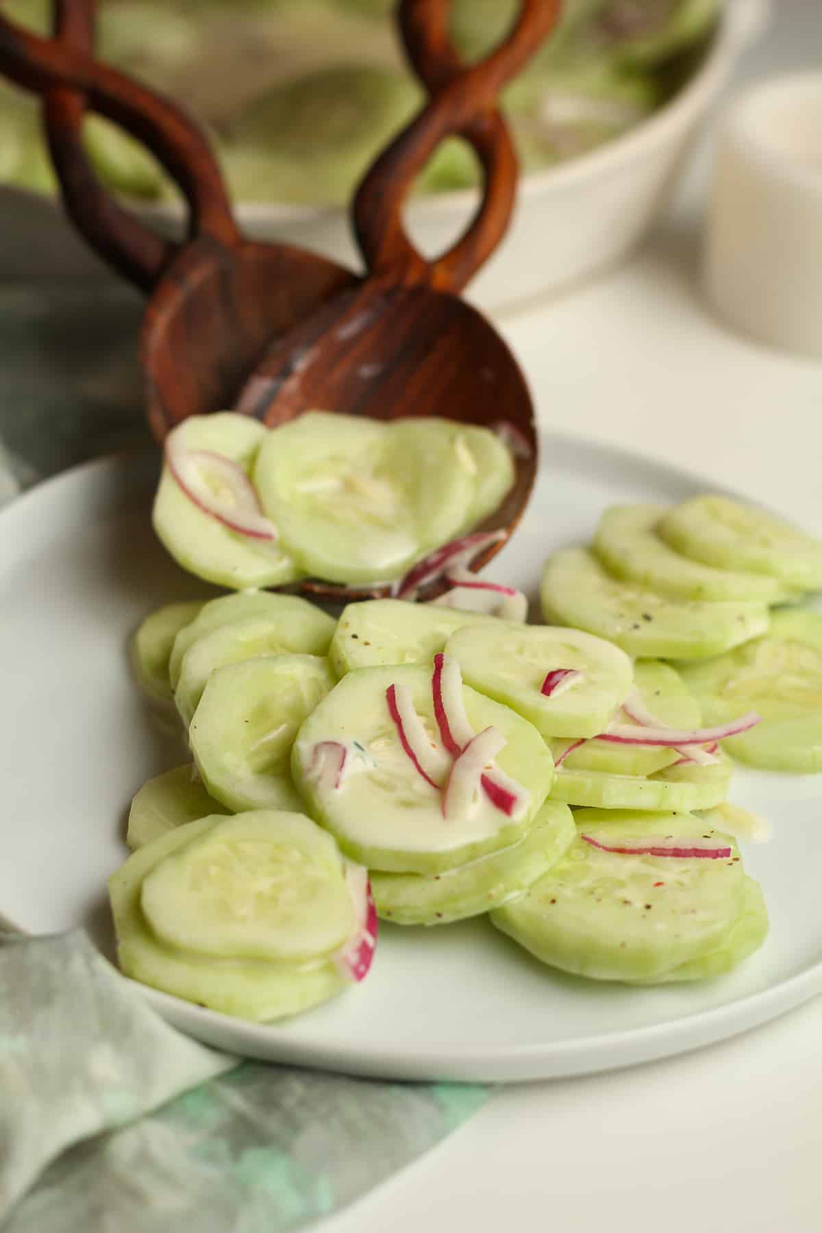 Two wooden spoons serving sliced cucumbers.