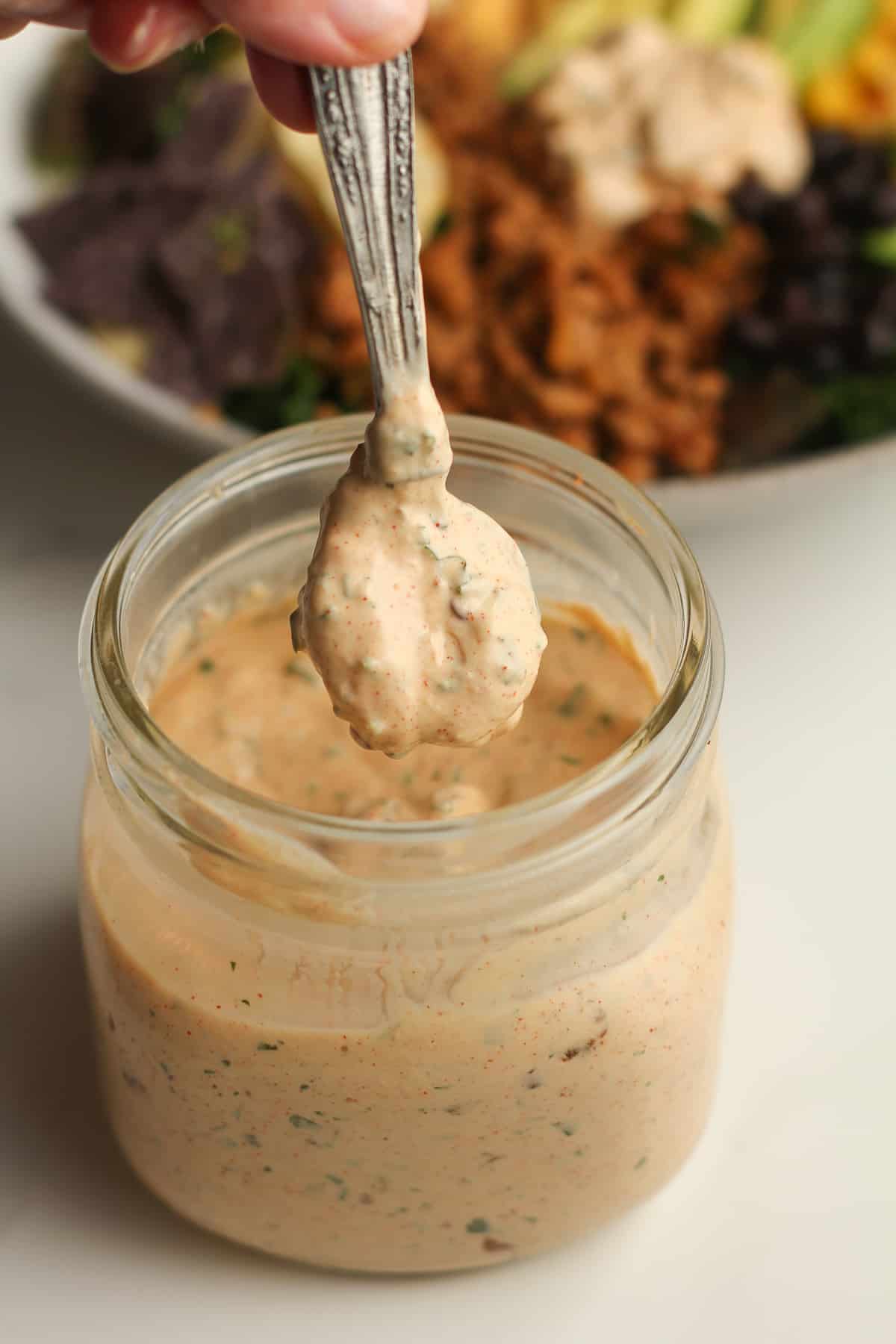 A jar of chipotle ranch with a teaspoon over top.