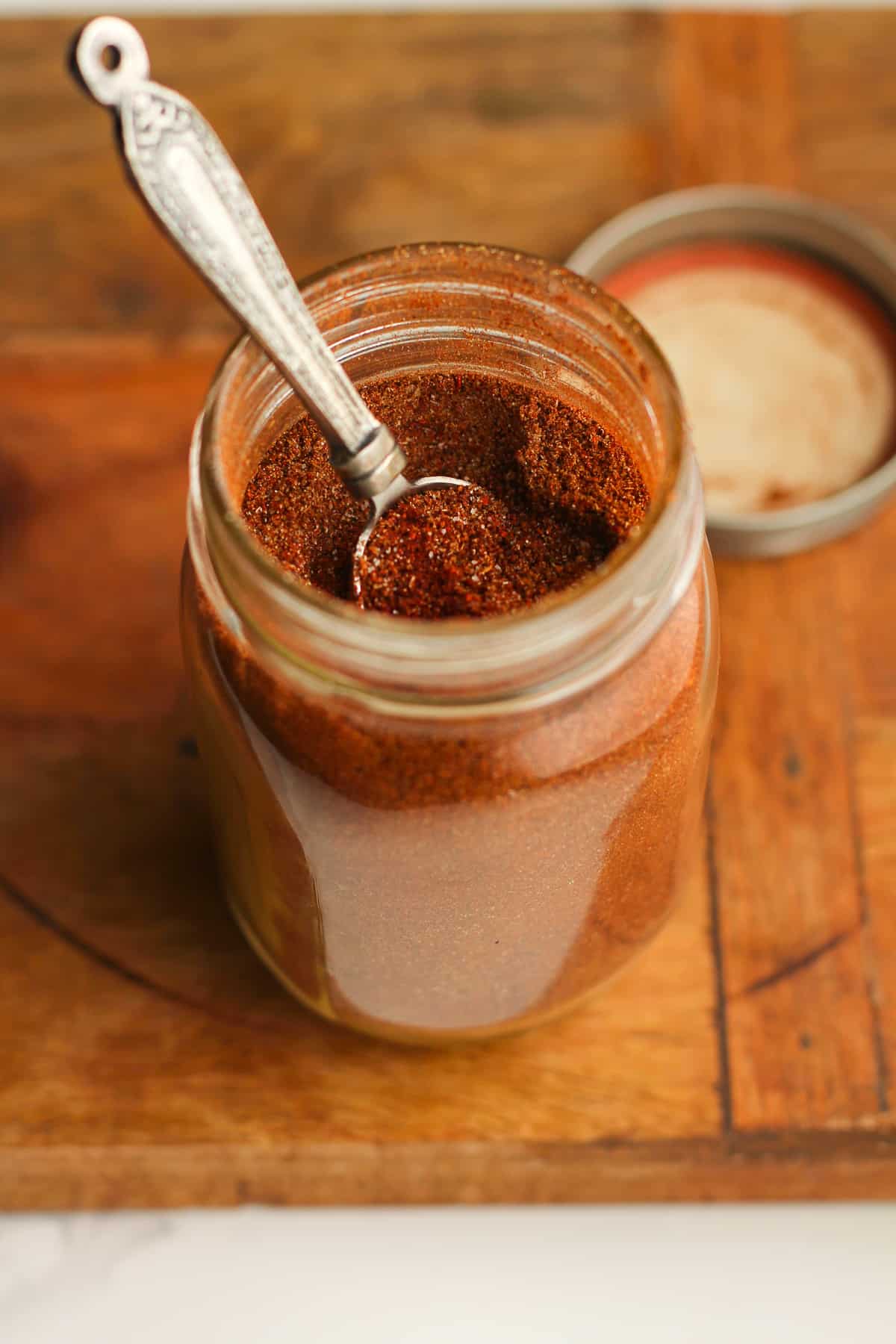 A jar of the homemade seasoning, with a teaspoon.