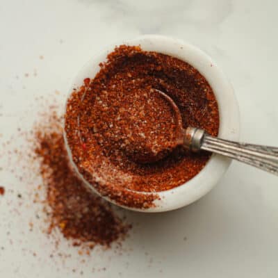 A small bowl of homemade taco seasoning with a teaspoon.