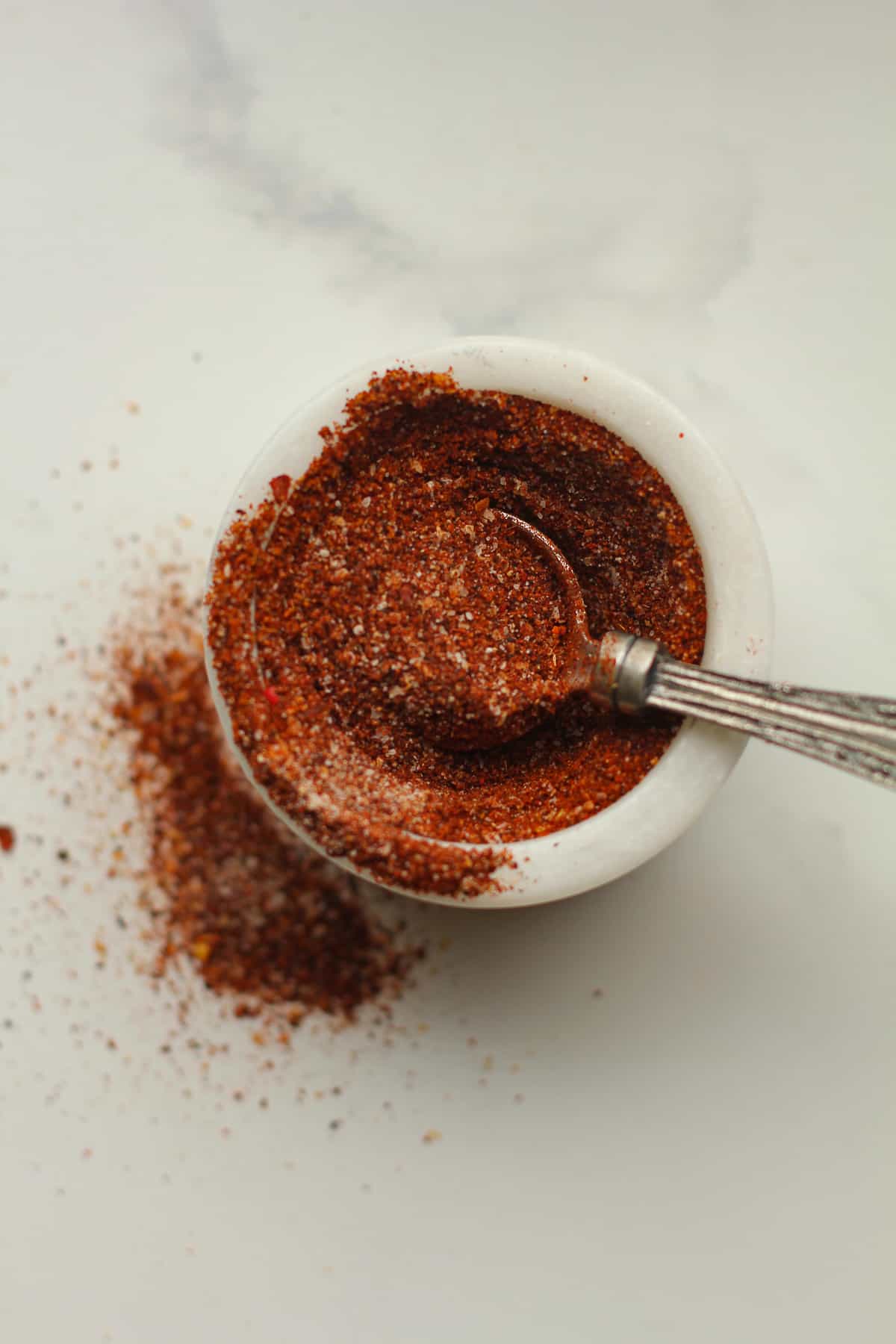 A small bowl of homemade taco seasoning with a teaspoon.