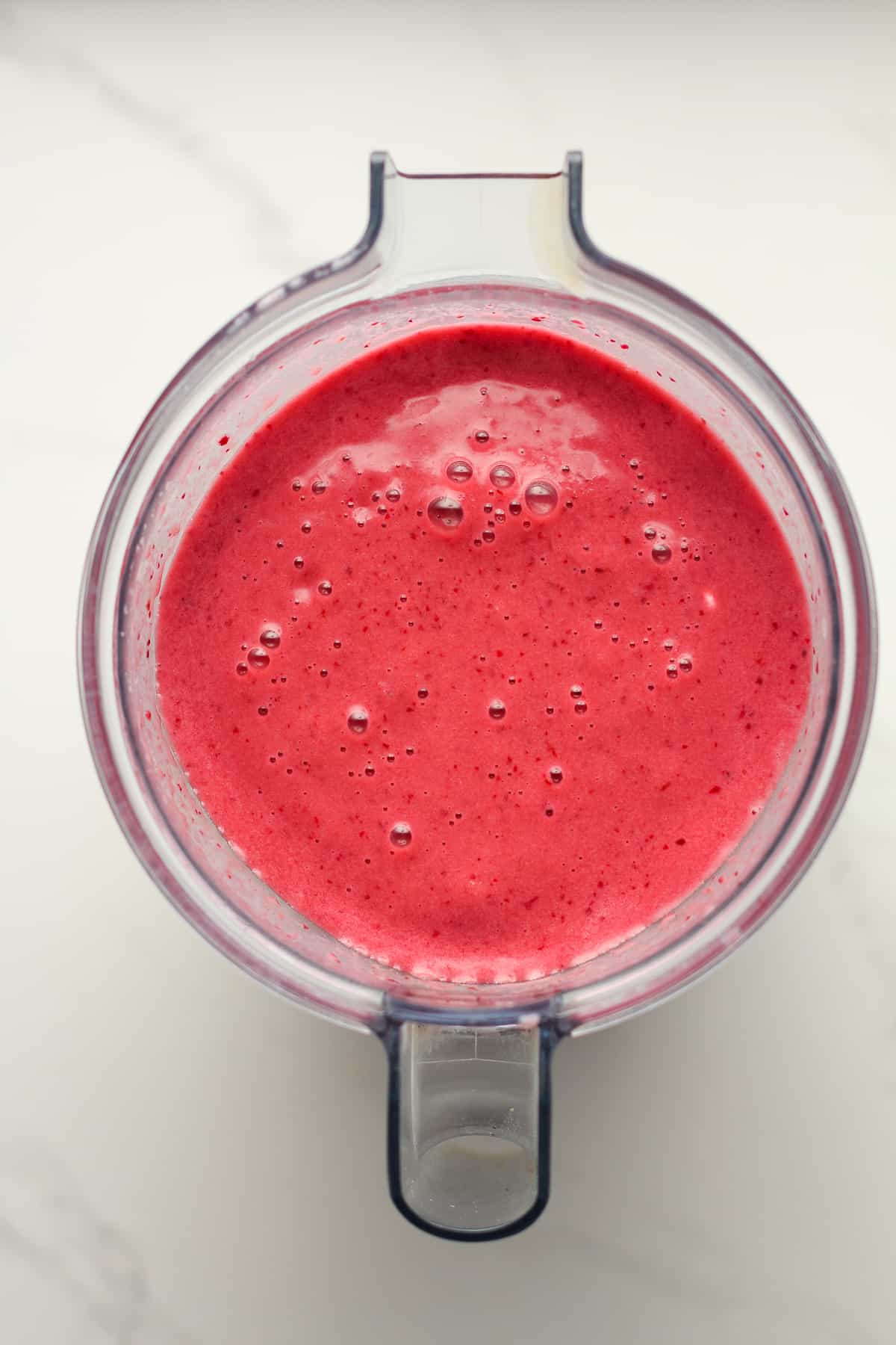 A pitcher of cherry smoothies in a blender.