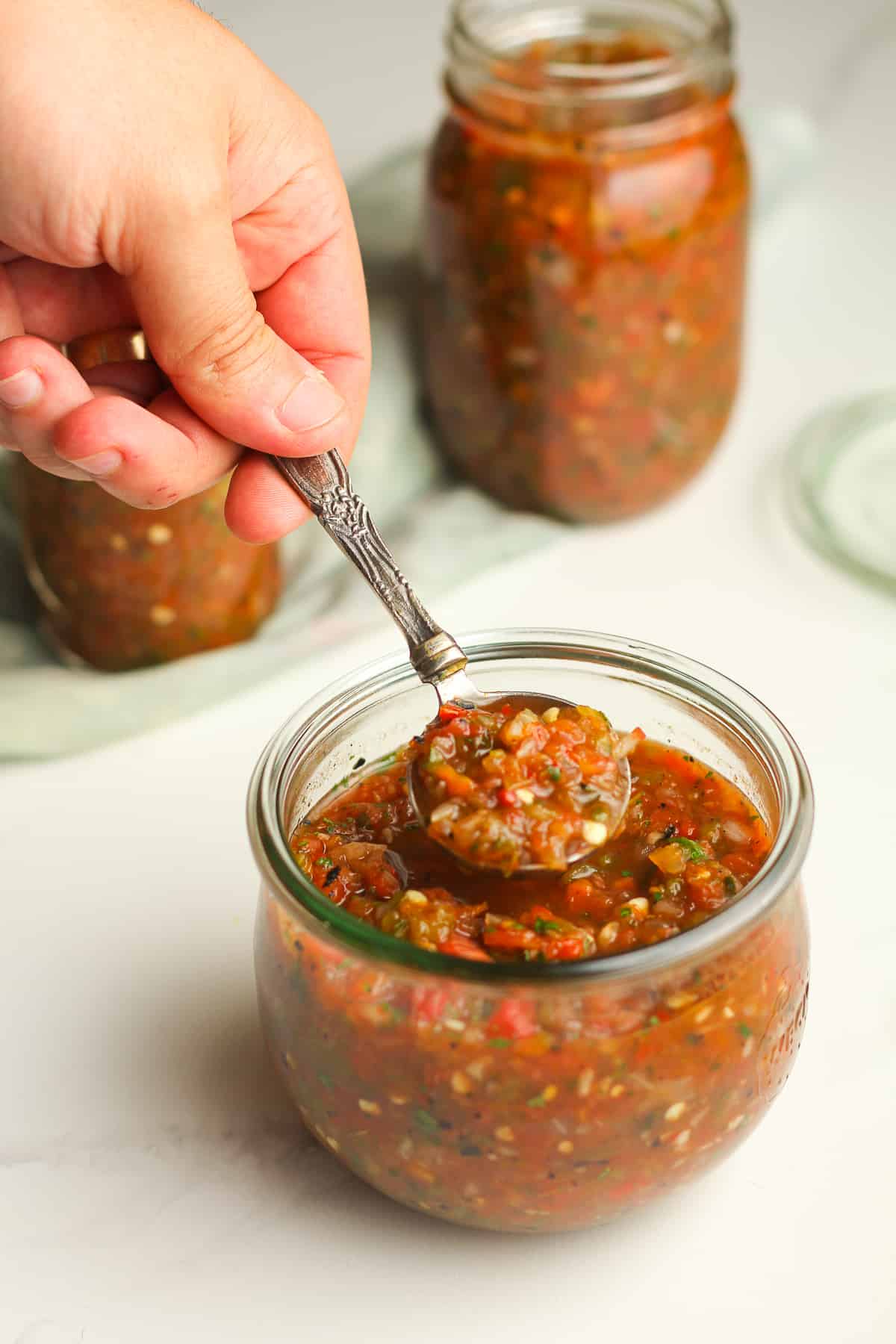 A spoonful of salsa over a jar.