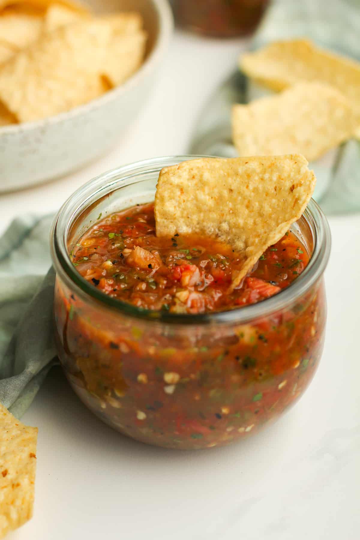 Side shot of grilled salsa with a chip.