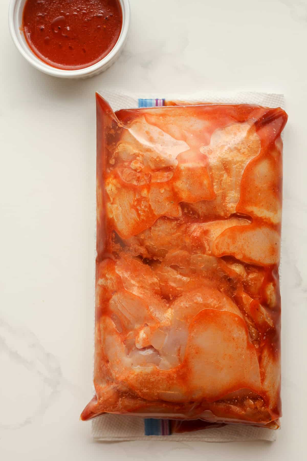 A bag of chicken breasts marinated in buffalo sauce.