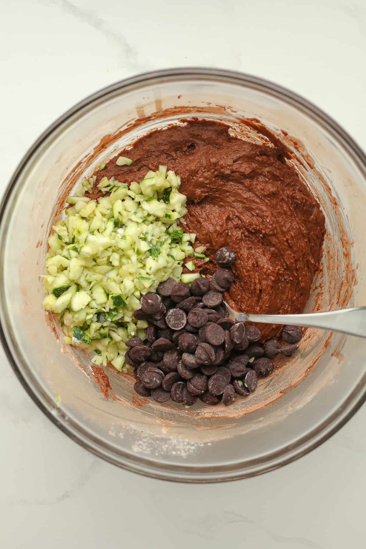 A bowl of the batter with zucchini and chocolate chips on top.