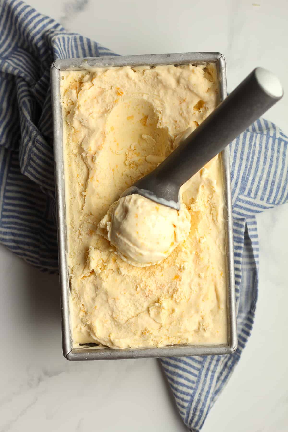 Peach ice cream with an ice cream scoop.