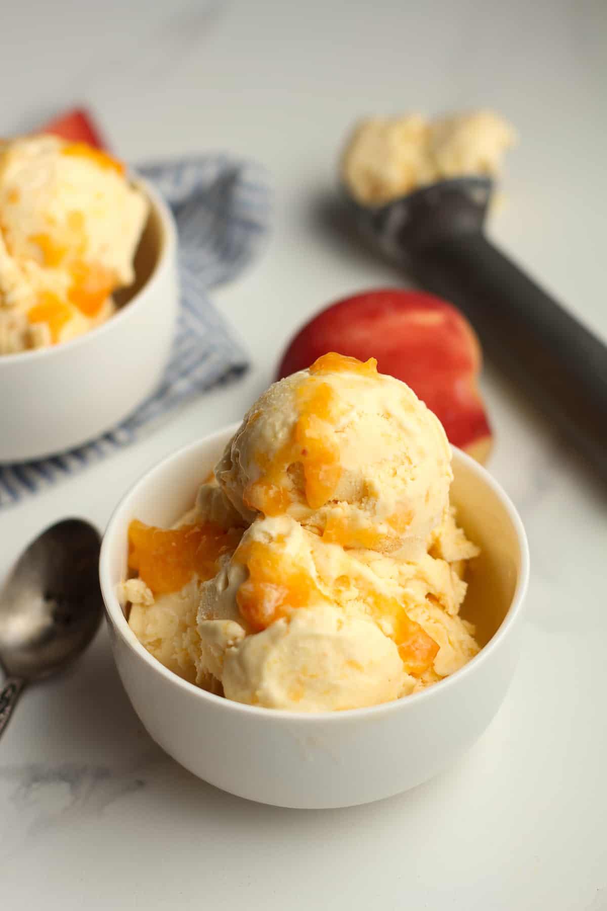 Side shot of two bowls of peach ice cream.
