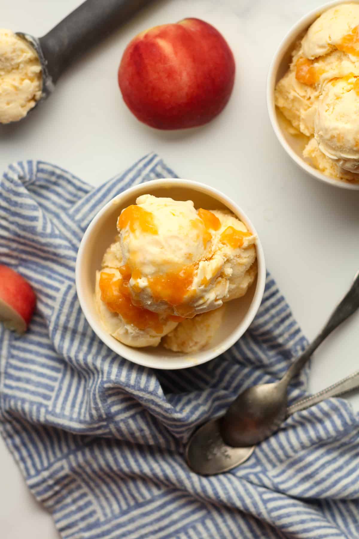 A spoonful of homemade peach ice cream, by a bowl.