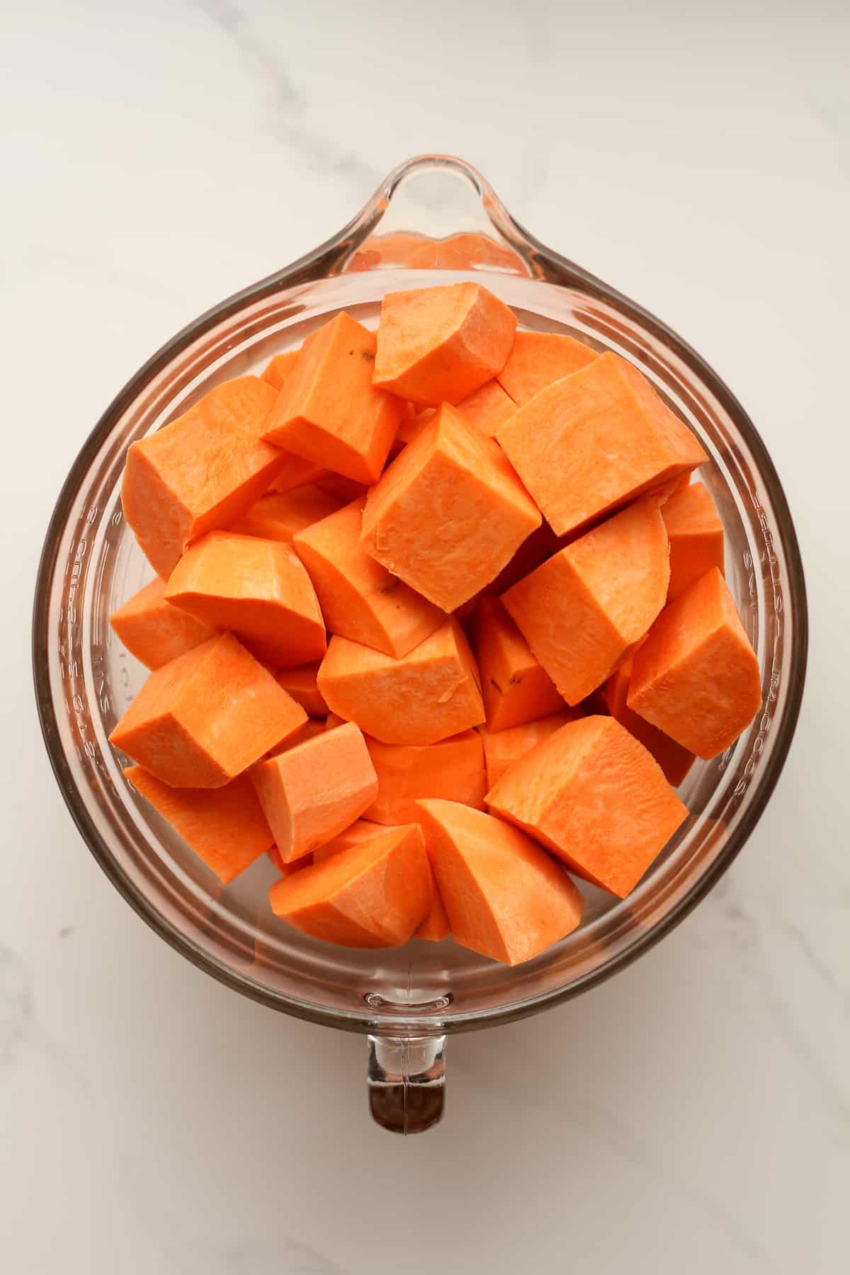 A large measuring cup with chopped sweet potatoes.