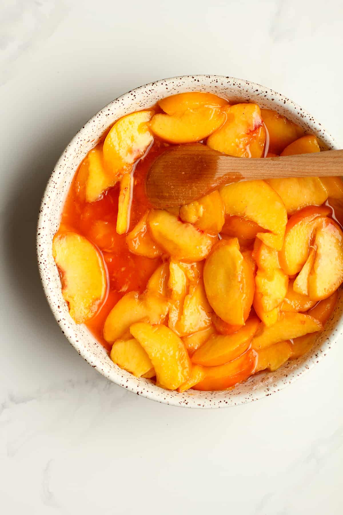 A bowl of peaches with juice.