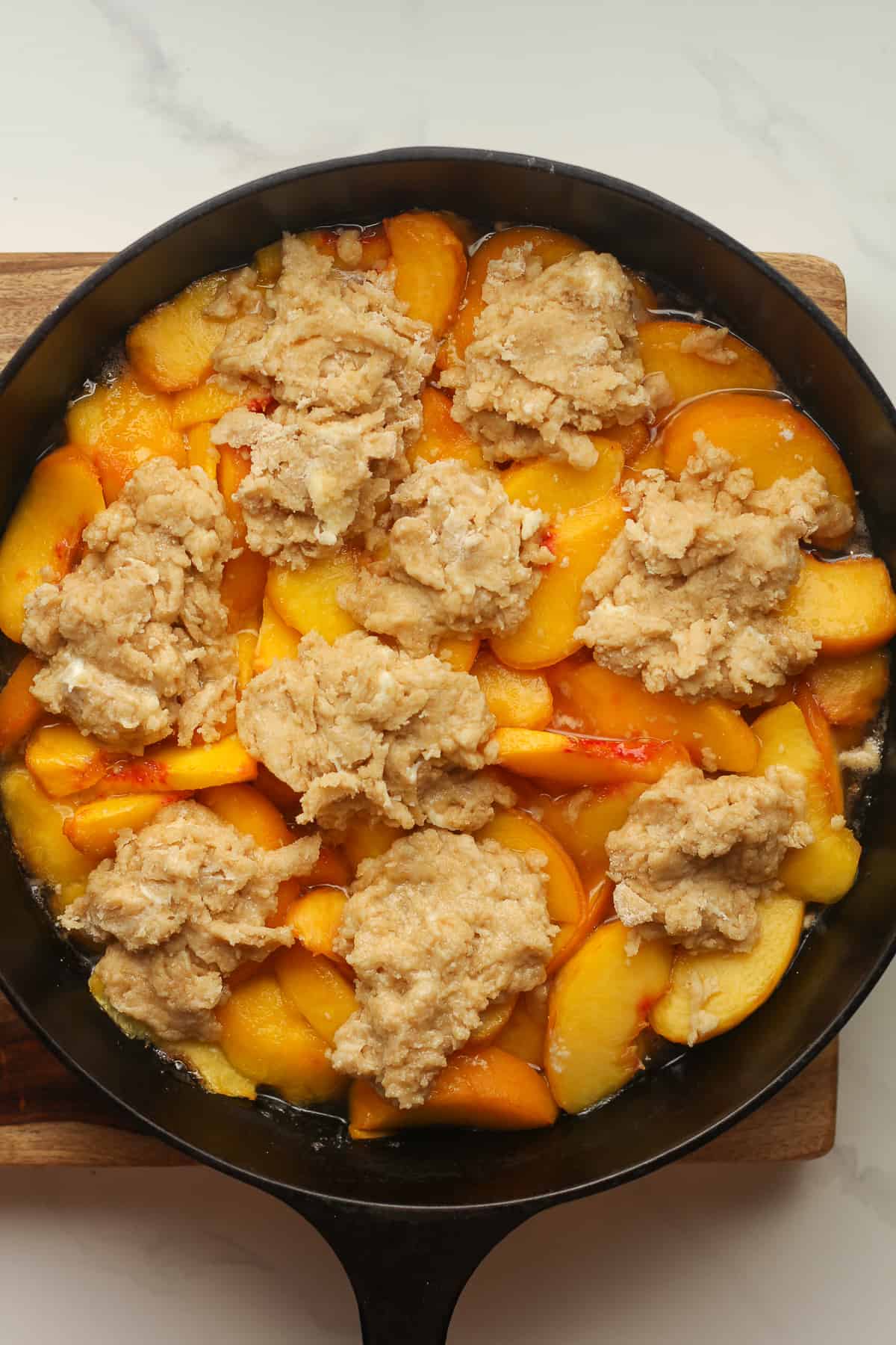 A skillet of peaches plus the raw cobbler topping.