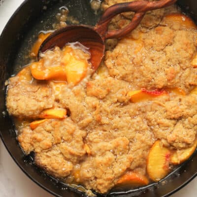 Overhead shot of skillet peach cobbler with a serving missing.