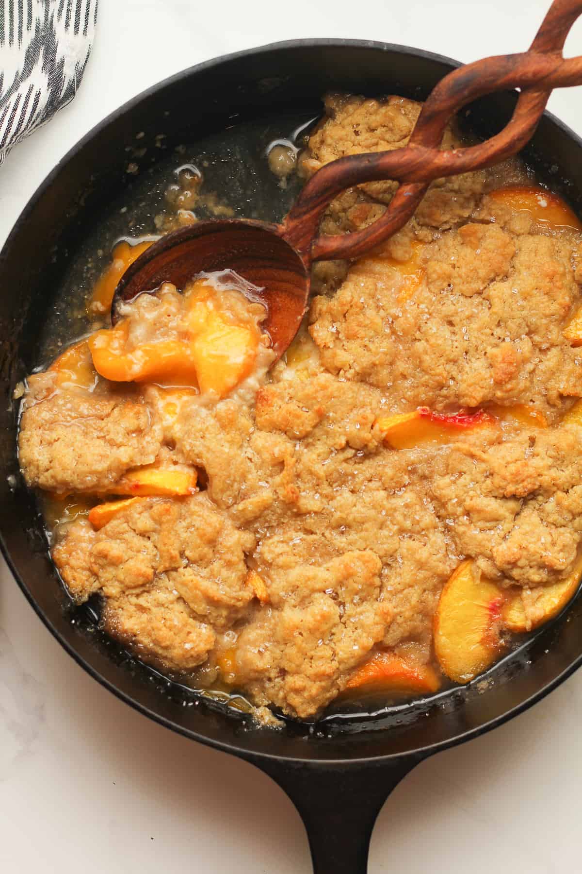 Overhead shot of skillet peach cobbler with a serving missing.