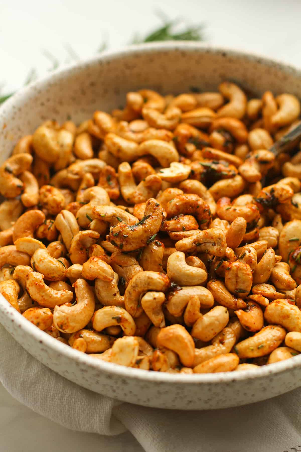 Side shot of a bowl of rosemary cashews.