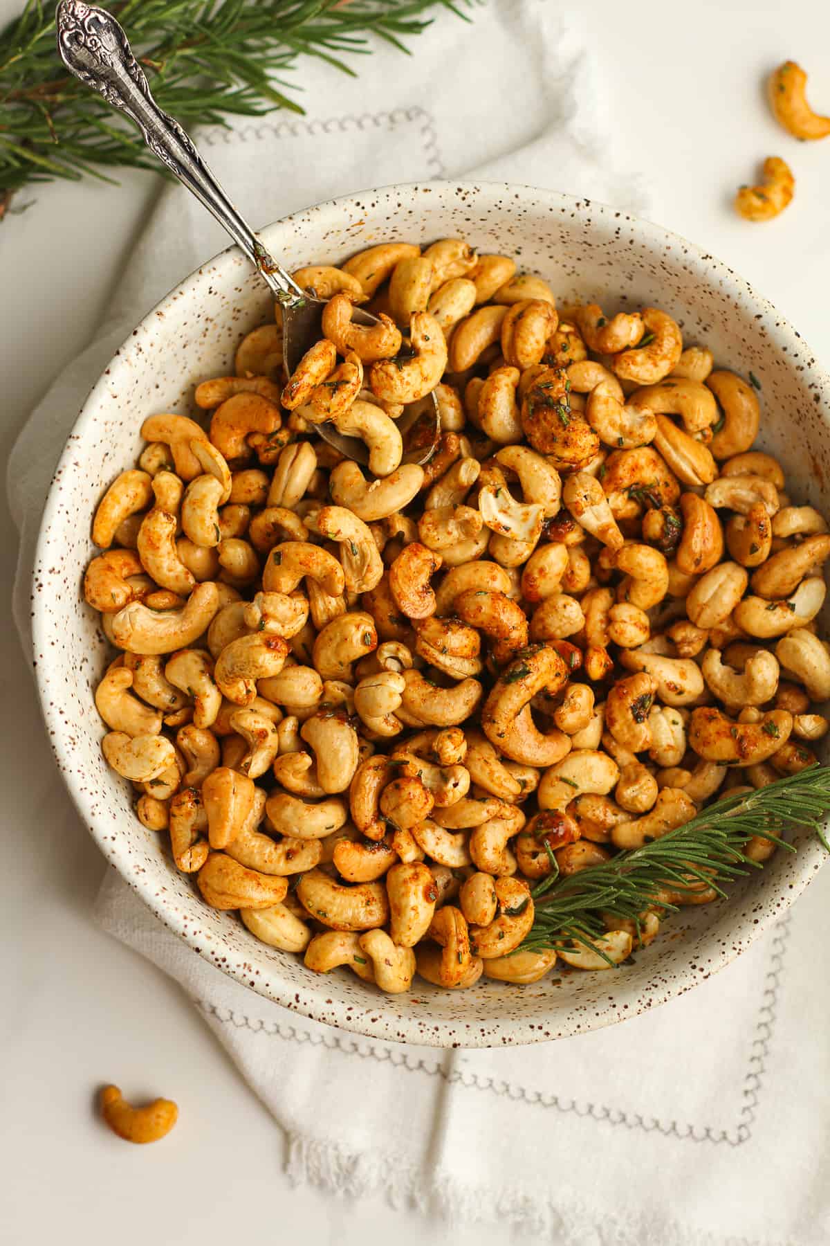 Overhead shot of a bowl of roasted rosemary cashews with a spoon.