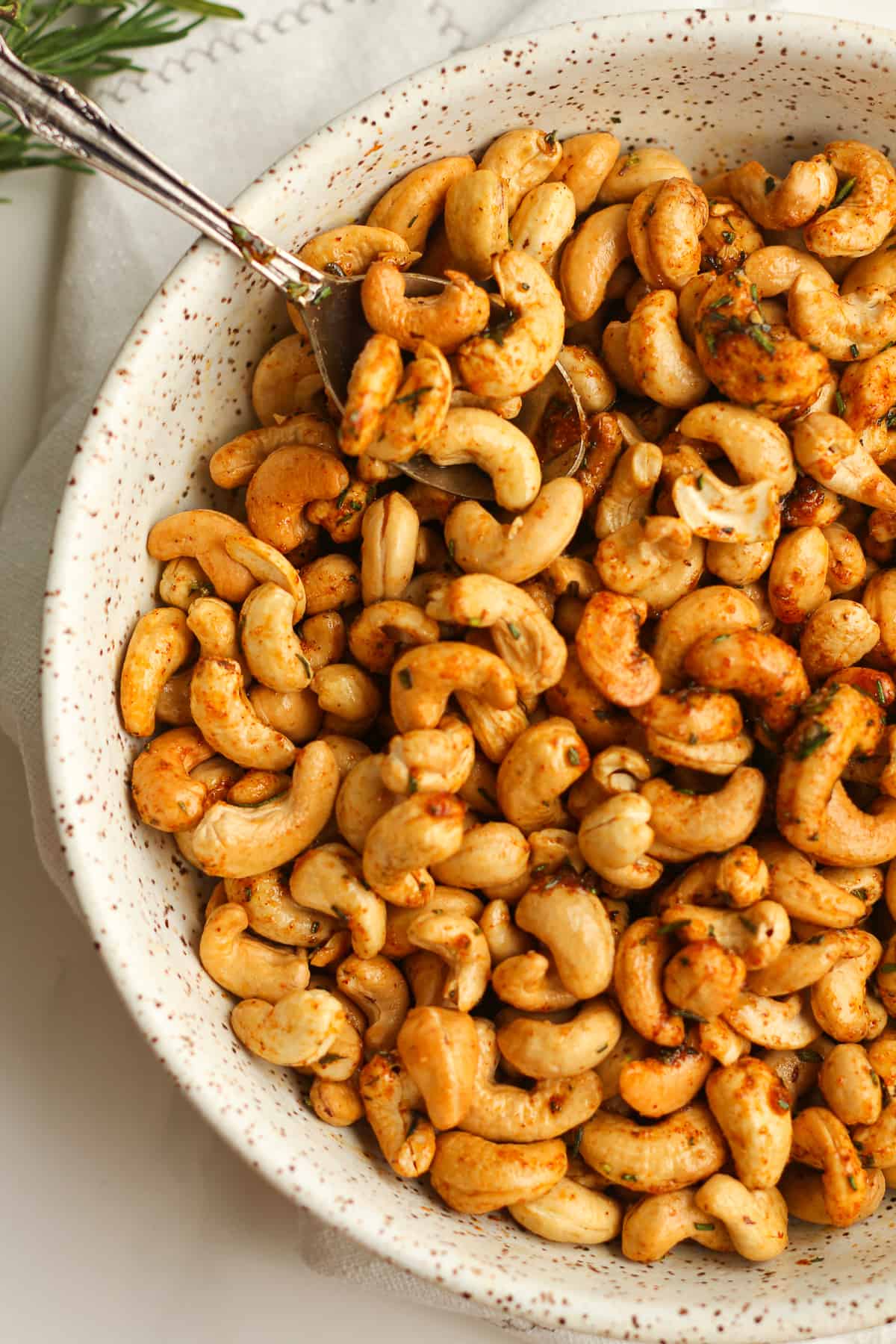 A closeup on a bowl of rosemary cashews.