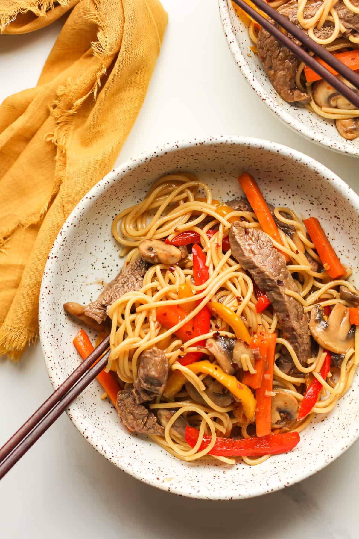 Two bowls of beef noodle stir fry.