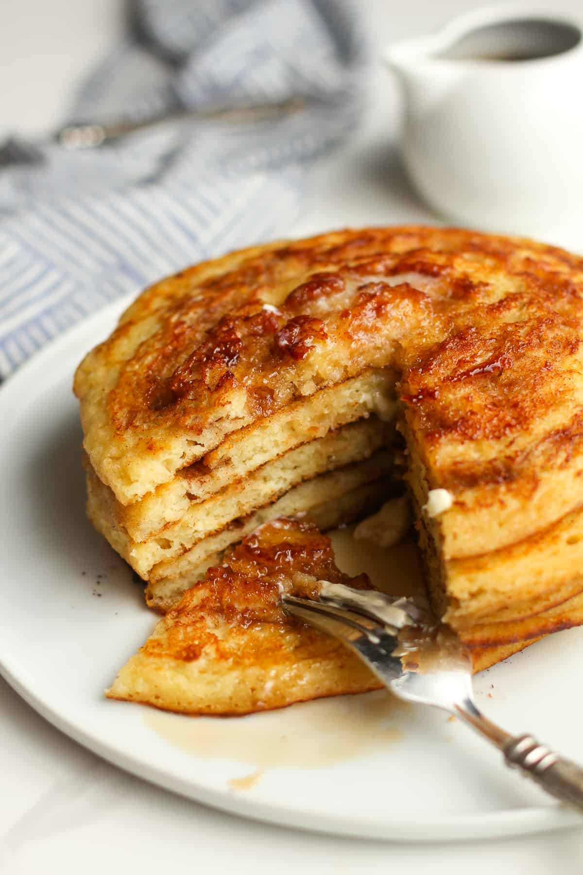 A plate of a stack of pancakes, with a section cut out.