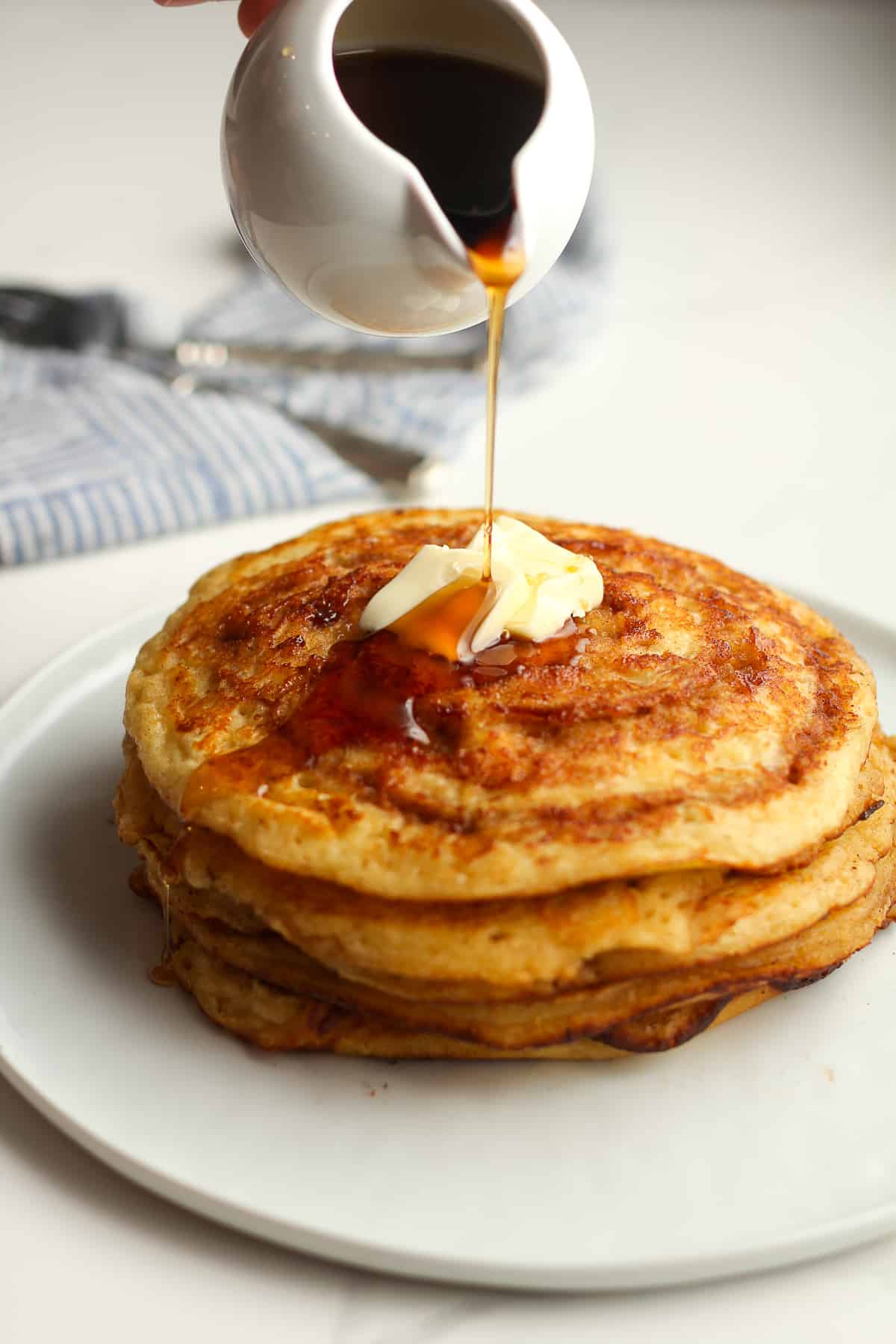 Some syrup drizzling on a stack of pancakes.