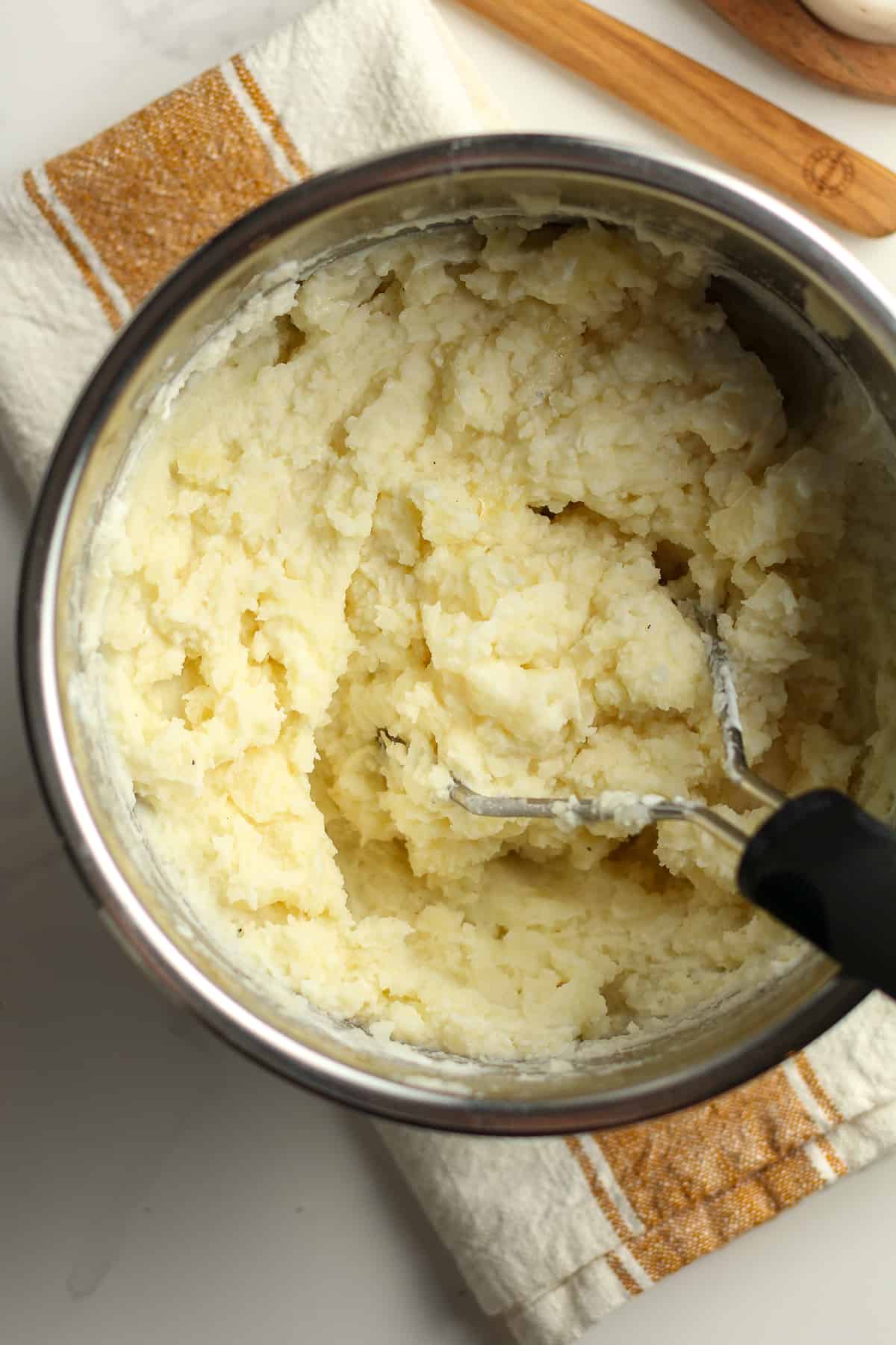 A potato masher mashing the potatoes.