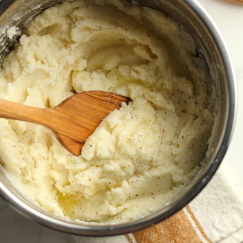 An instant pot full of garlic mashed potatoes, with a wooden spoon.