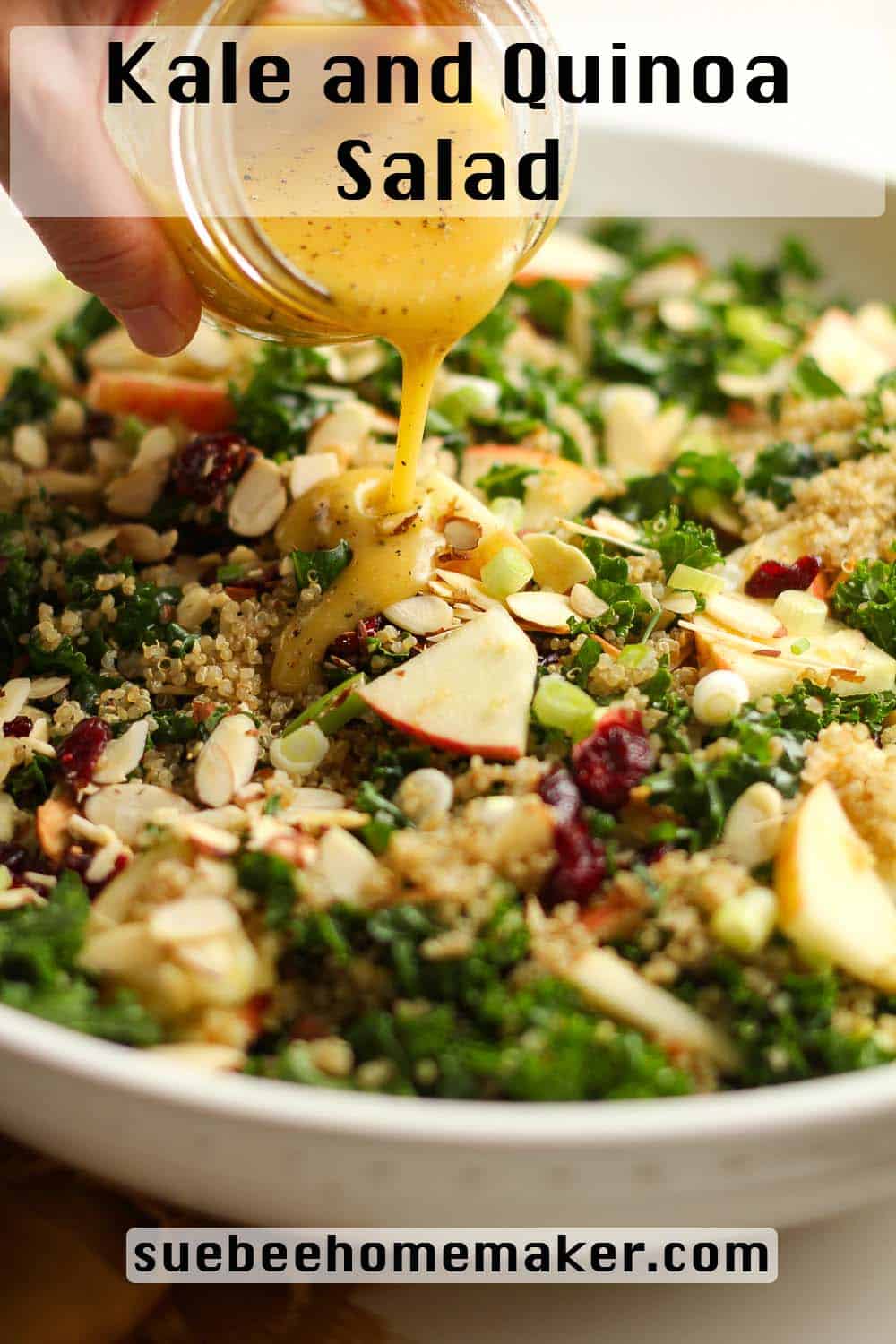 A hand drizzling dressing over a kale and quinoa salad.