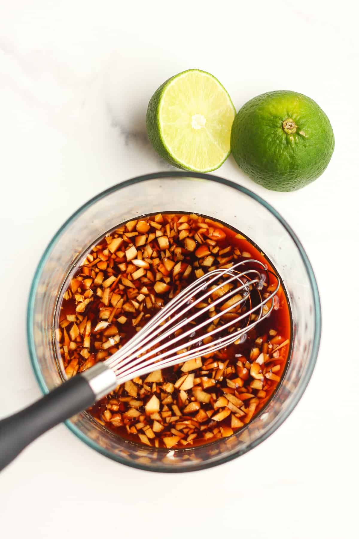 A bowl of the Asian marinade with limes.