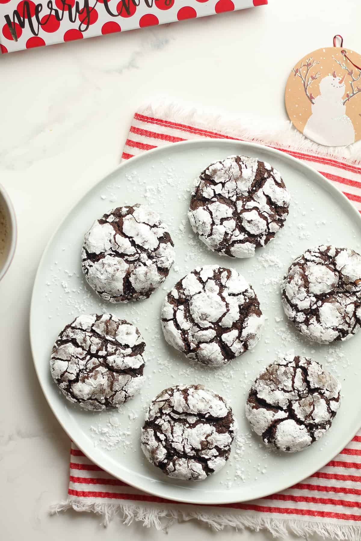 A plate of brownie crinkle cookies on a red and white napkin.