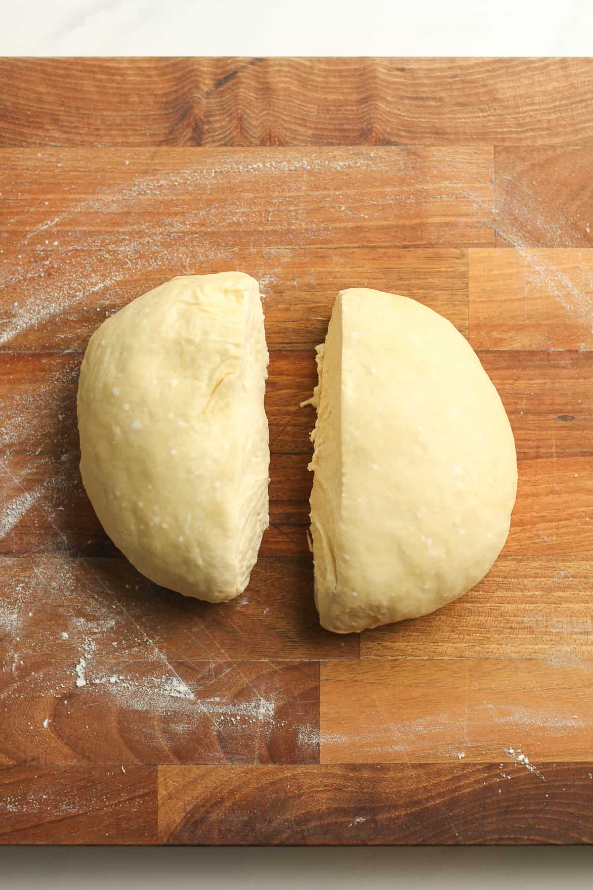 A round of flatbread dough cut in half.