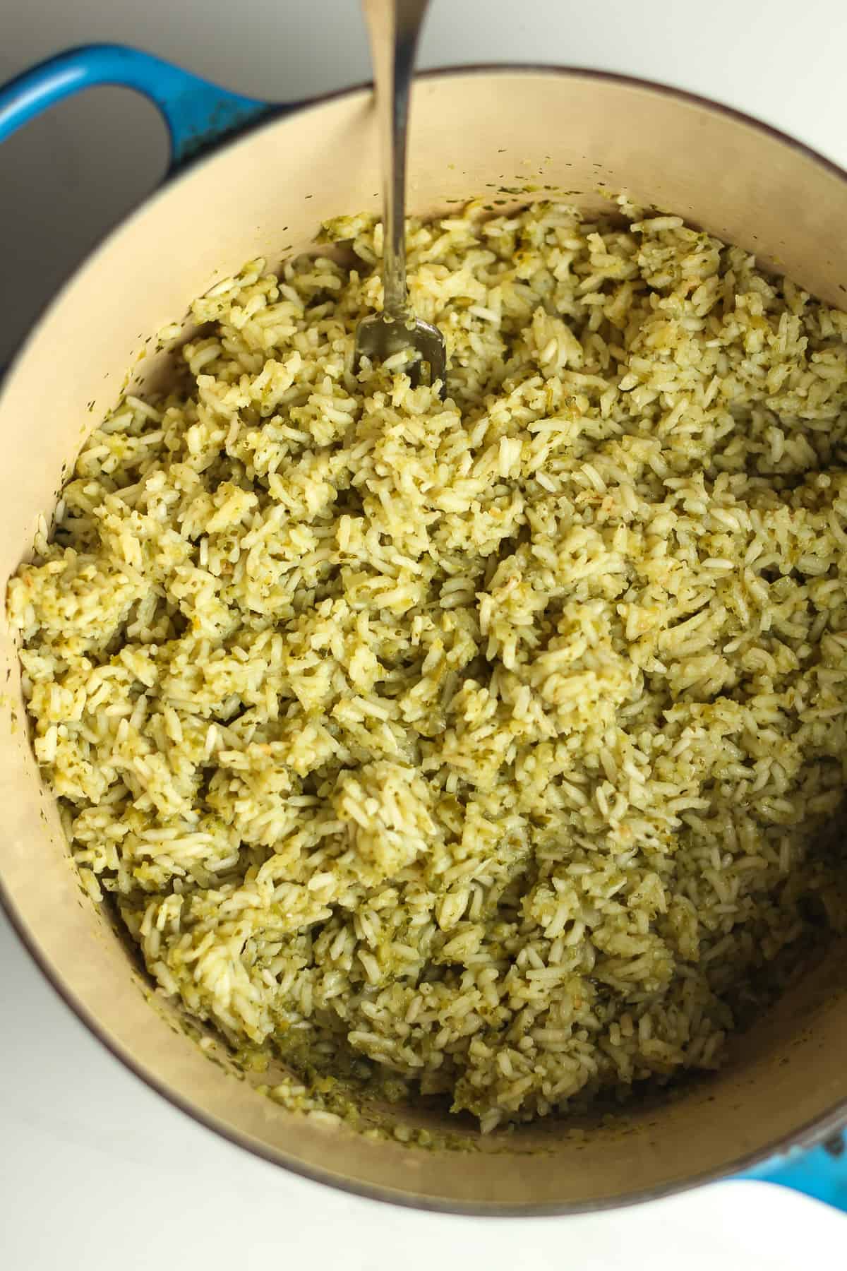 A stock pot of green Chile rice with a fork.