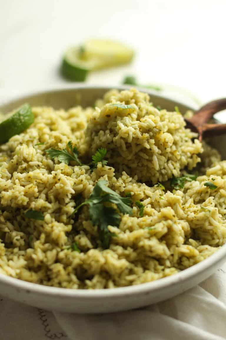 Side shot of a bowl of green rice with a spoon.