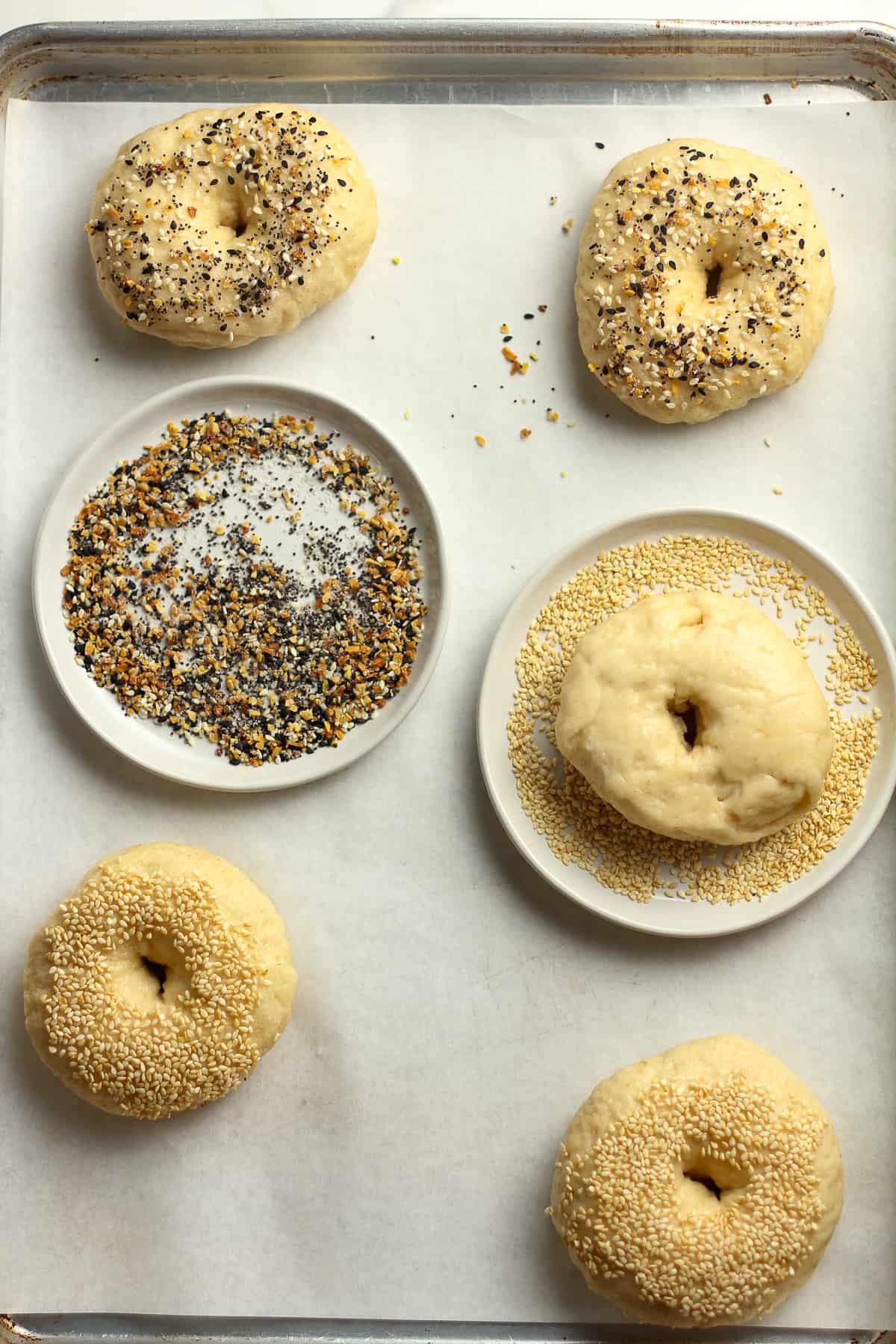 A pan of the bagels showing them dunked in toppings.