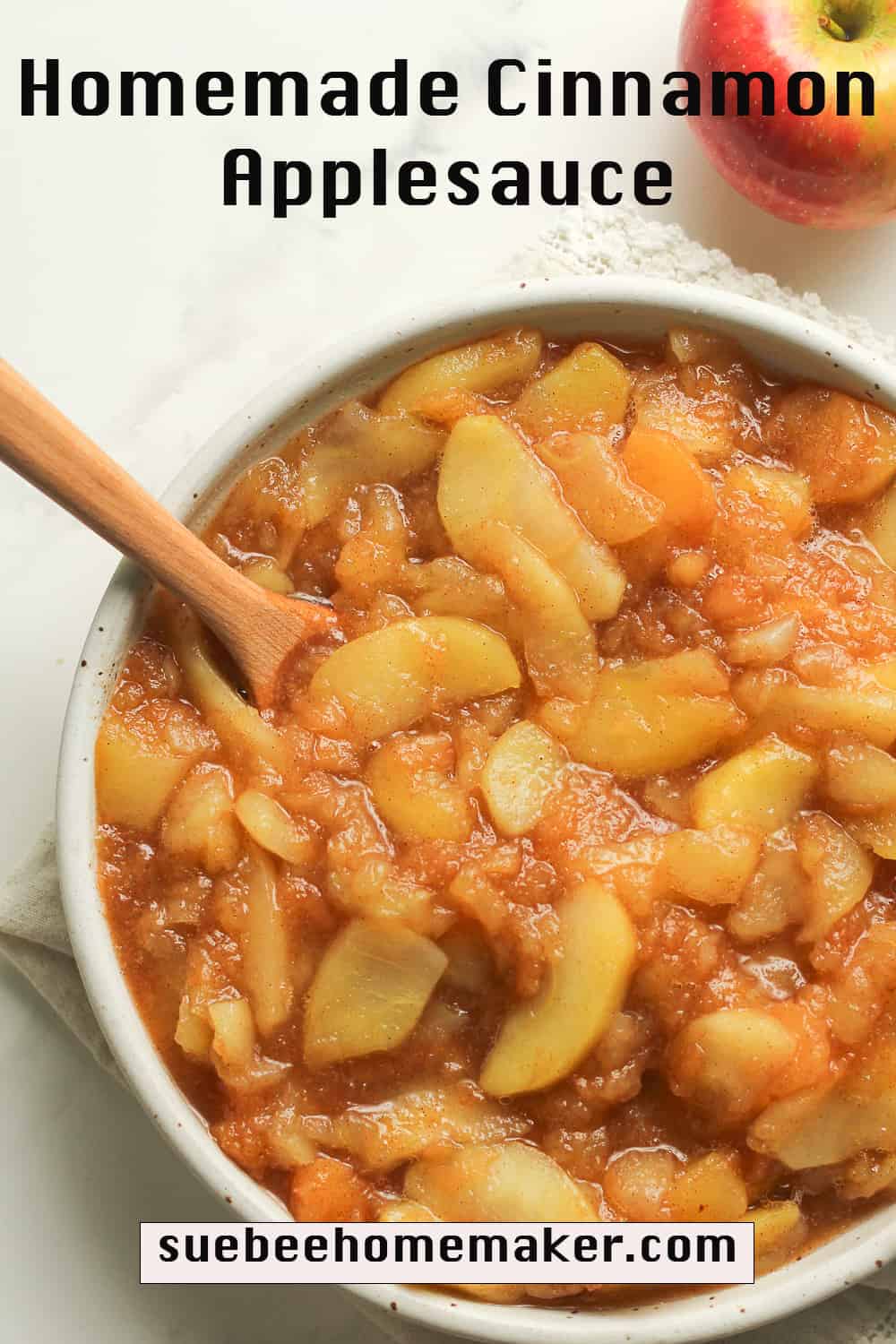 A bowl of homemade cinnamon applesauce with a wooden spoon.