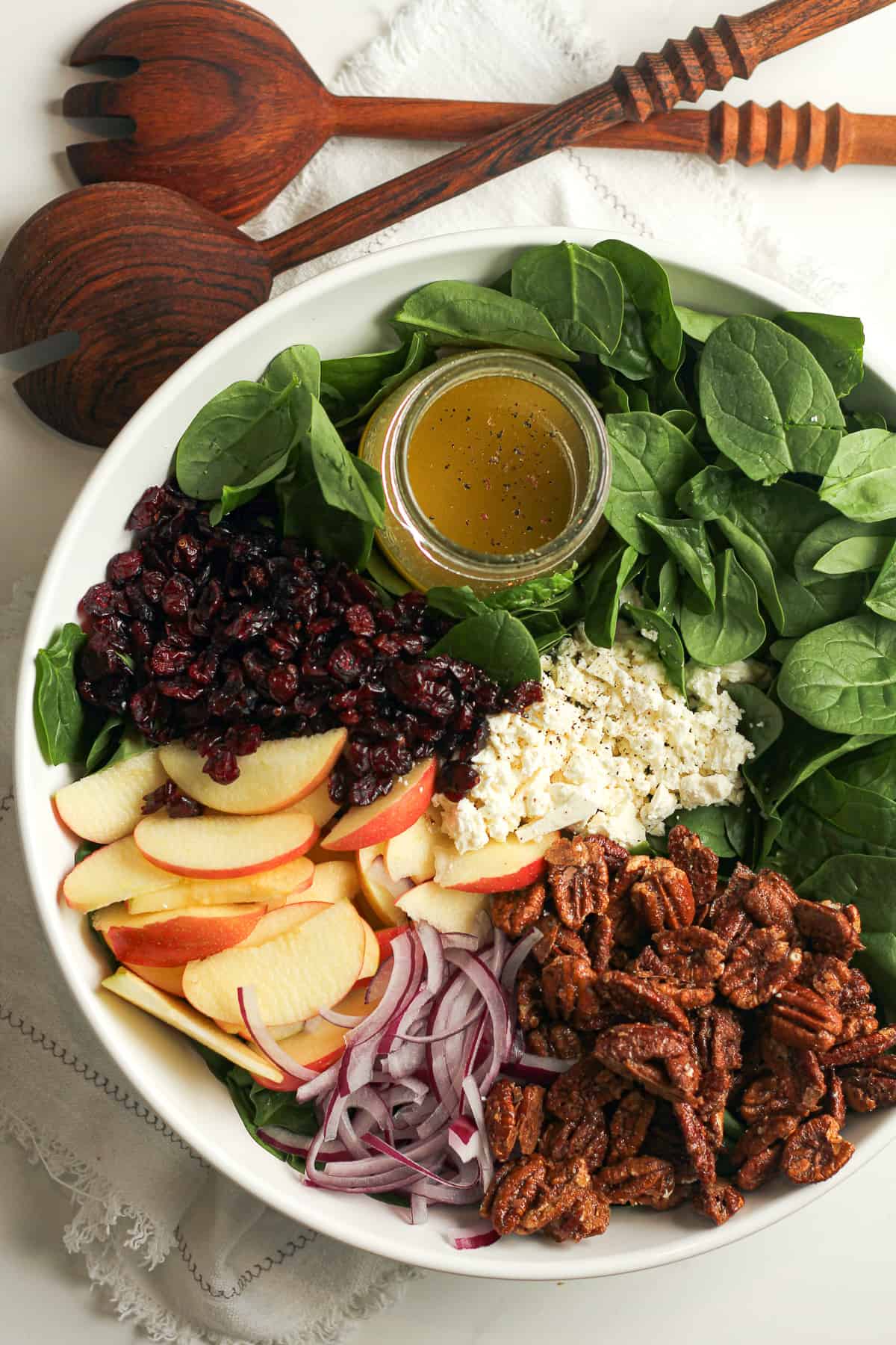 A large salad, divided by ingredient with wooden spoons.