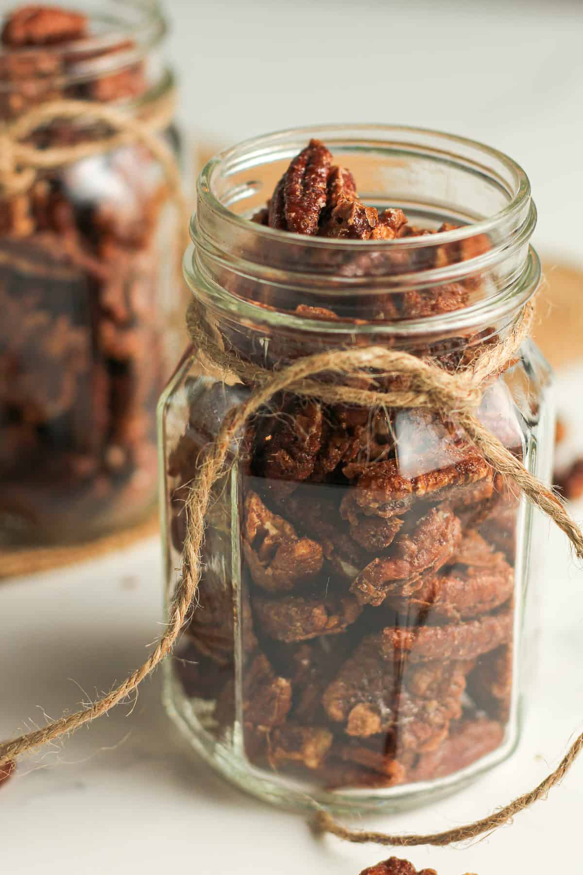 Two jars of caramelized pecans, with twine.