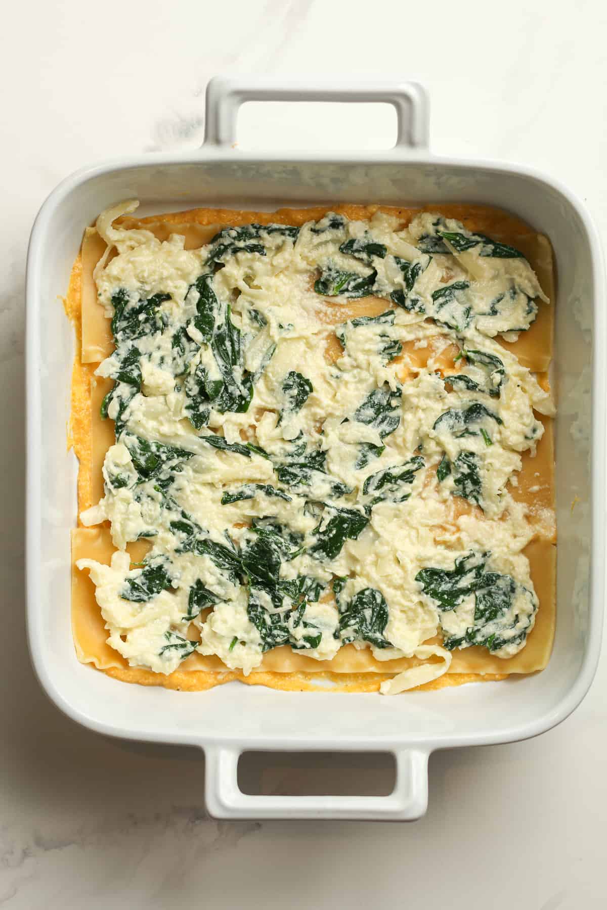 The dish with the cheese and spinach layer.
