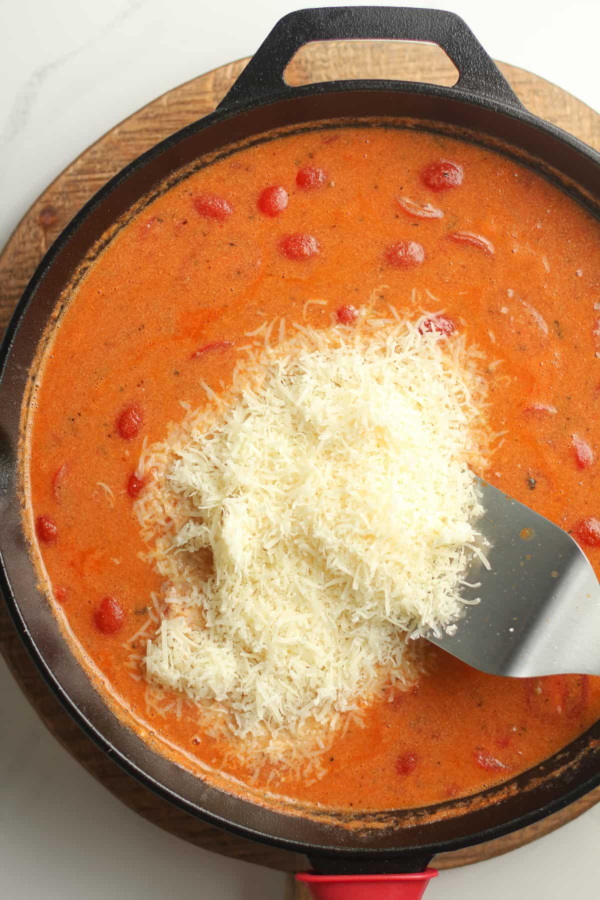A cast iron skillet with the tomato mixture and parmesan on top.