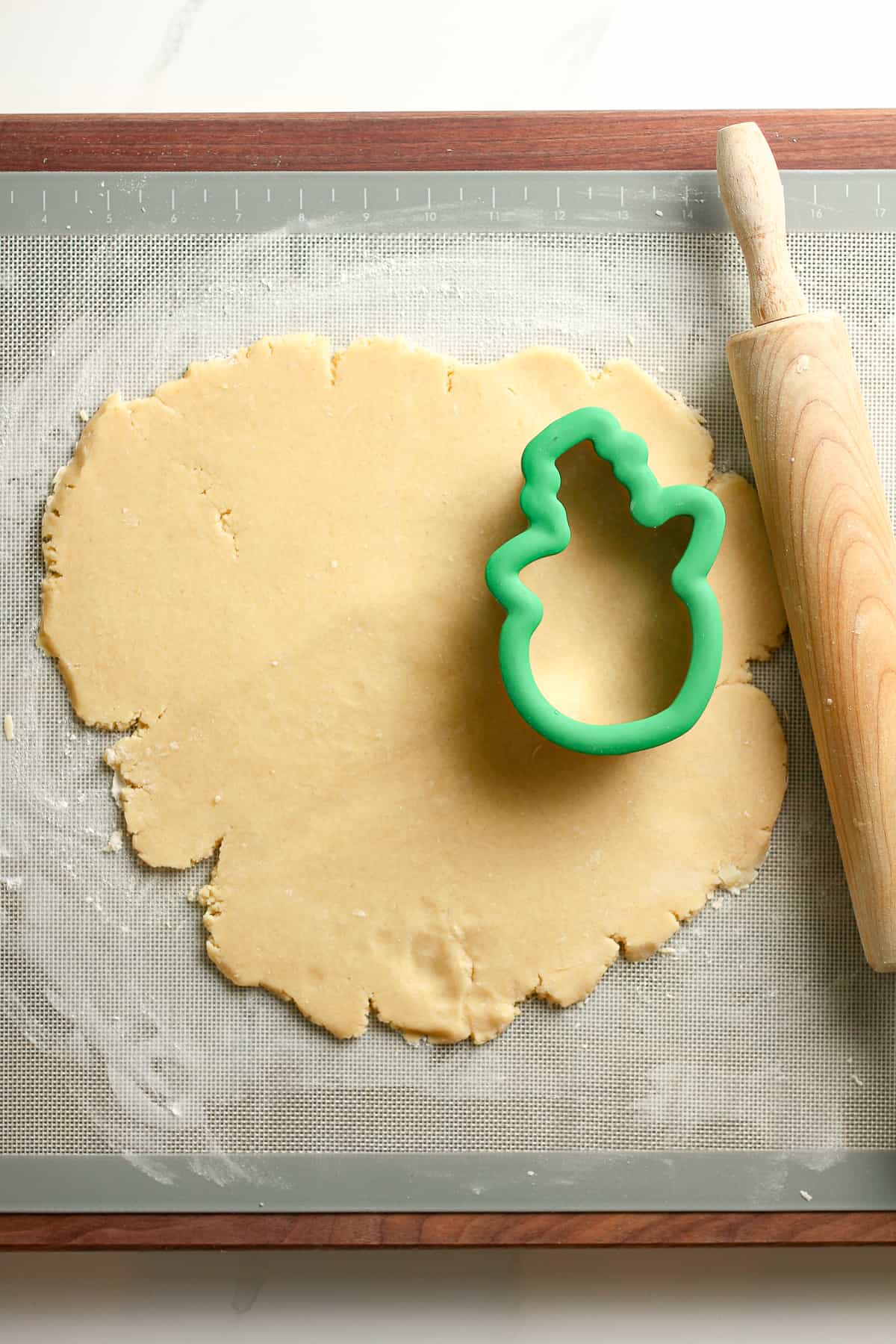 Some rolled out dough with a cookie cutter snowman.