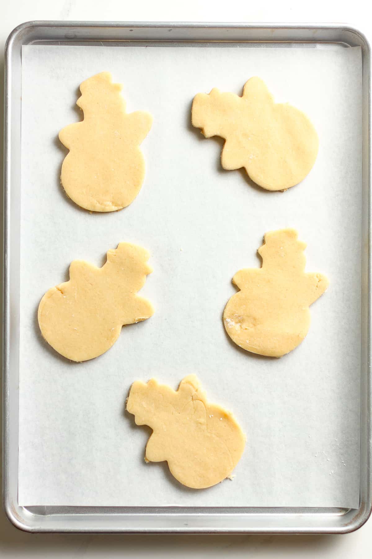 A baking sheet with the cut out snowmen.