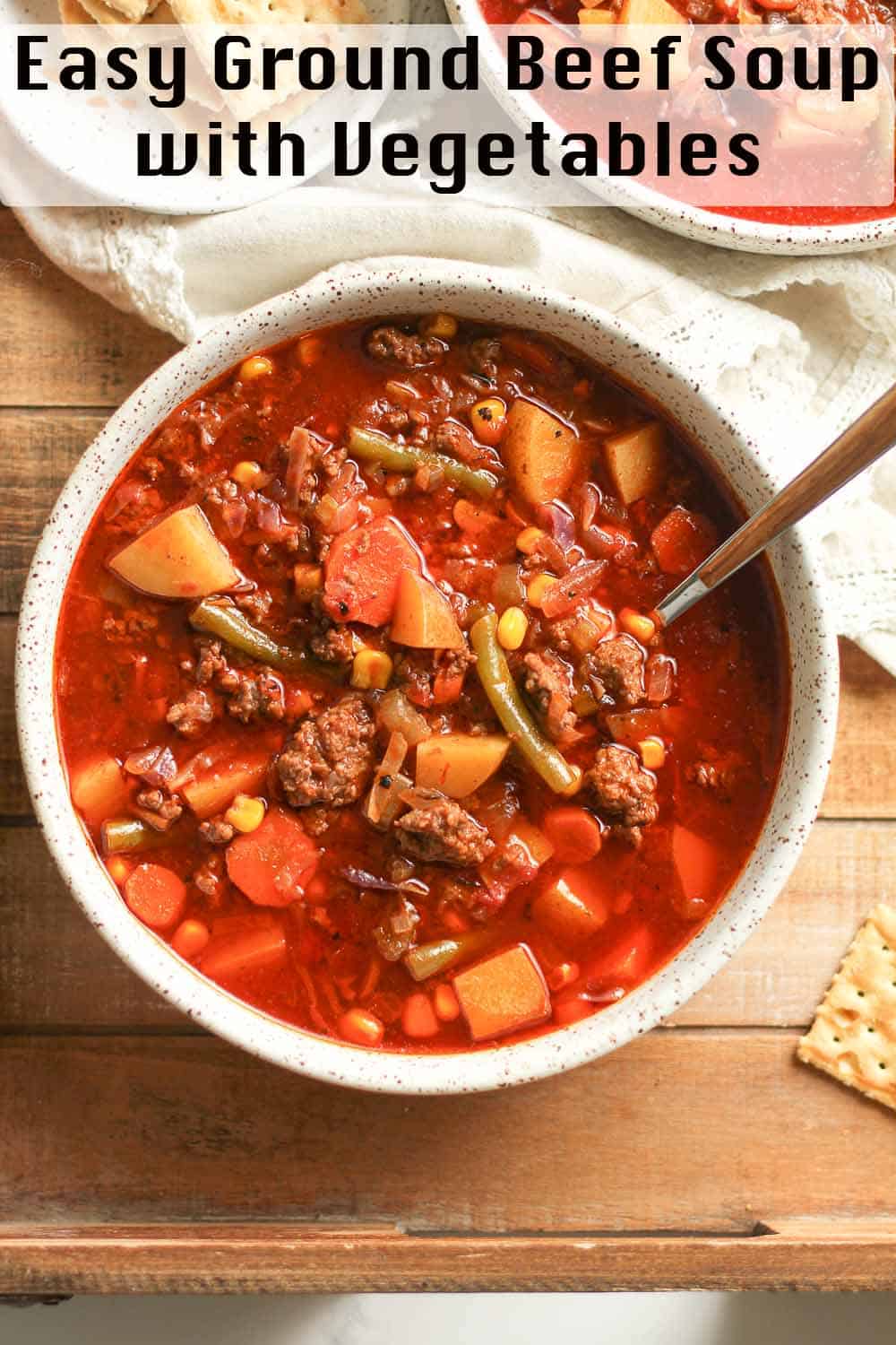 A bowl of ground beef soup with vegetables.