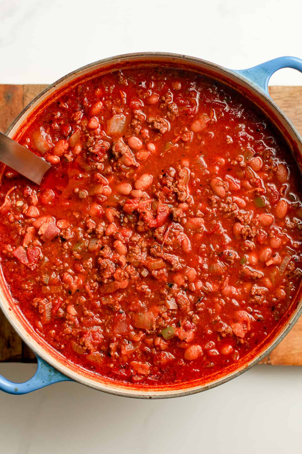 Overhead shot of a stock pot of chili with a soup ladle.