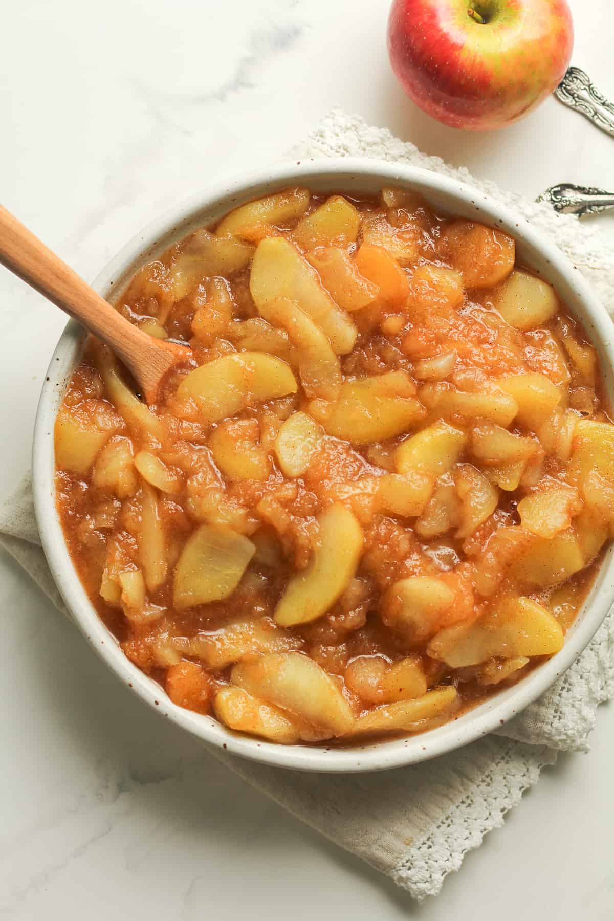 A bowl of cinnamon applesauce, with a wooden spoon.